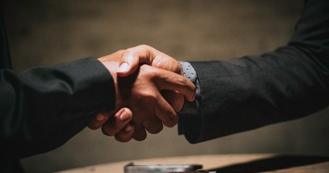 Two people shaking hands over a table, representing a partnered Bitcoin mining arrangement split automatically through ViaBTC Revenue Sharing