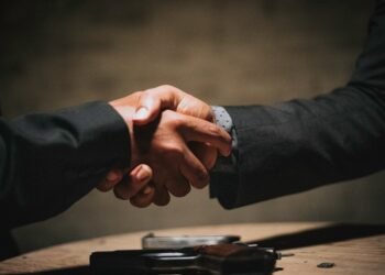 Two people shaking hands over a table, representing a partnered Bitcoin mining arrangement split automatically through ViaBTC Revenue Sharing