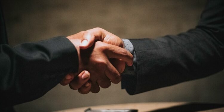 Two people shaking hands over a table, representing a partnered Bitcoin mining arrangement split automatically through ViaBTC Revenue Sharing